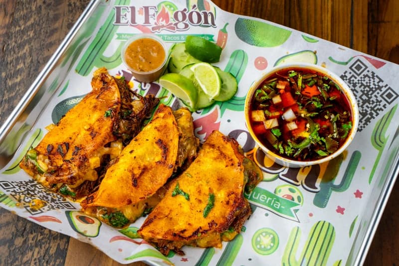 El Fogón quesabirria tacos with consomé on a branded serving tray in Playa del Carmen